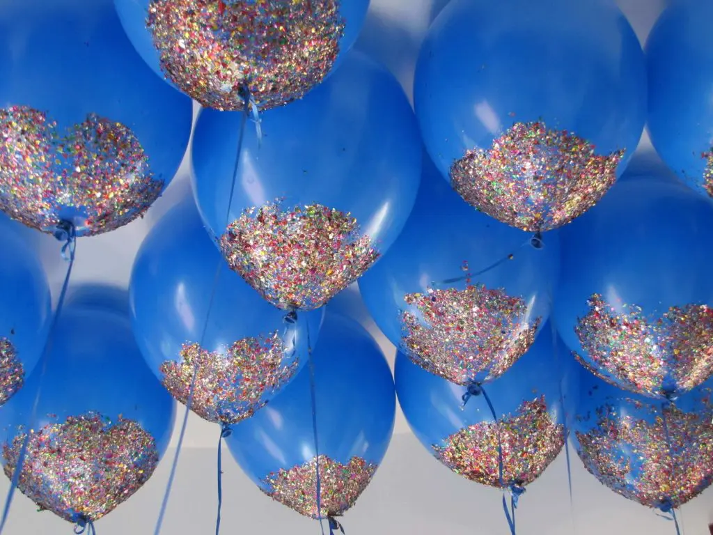 A group of colorful confetti balloons, including blue, gold, yellow, green, and burgundy, arranged together for an event party.