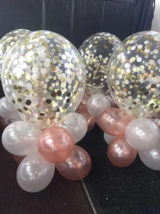 A stunning decoration featuring white and gold balloons, including golden confetti balloons and glitter balloons, along with a confetti table bouquet, perfect for adding a touch of glamour to any celebration, such as a happy birthday, in Brooklyn.