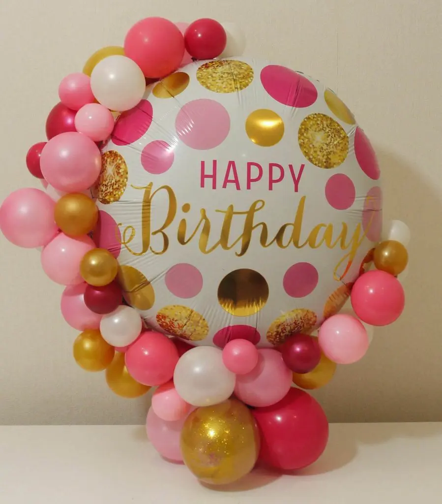 Balloons Lane in NYC creates a colorful and festive centerpiece for a birthday party, featuring a large mylar balloon in bright colors paired with a mix of pink latex balloons. The combination of the large, eye-catching mylar balloon and the playful pink latex balloons makes for a fun and cheerful decoration.