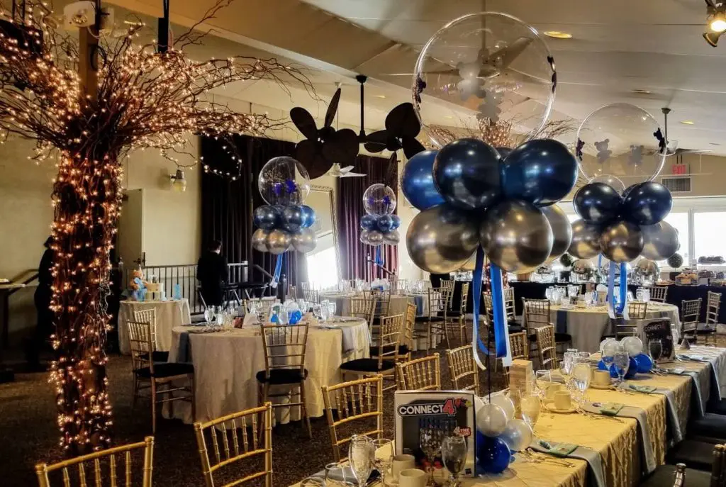 A beautiful and elegant centerpiece featuring Chrome Silver, Blue, White, and Chrome® Purple balloons arranged in a decorative manner. The centerpiece also includes clear bubble balloons, creating a stunning and unique display.