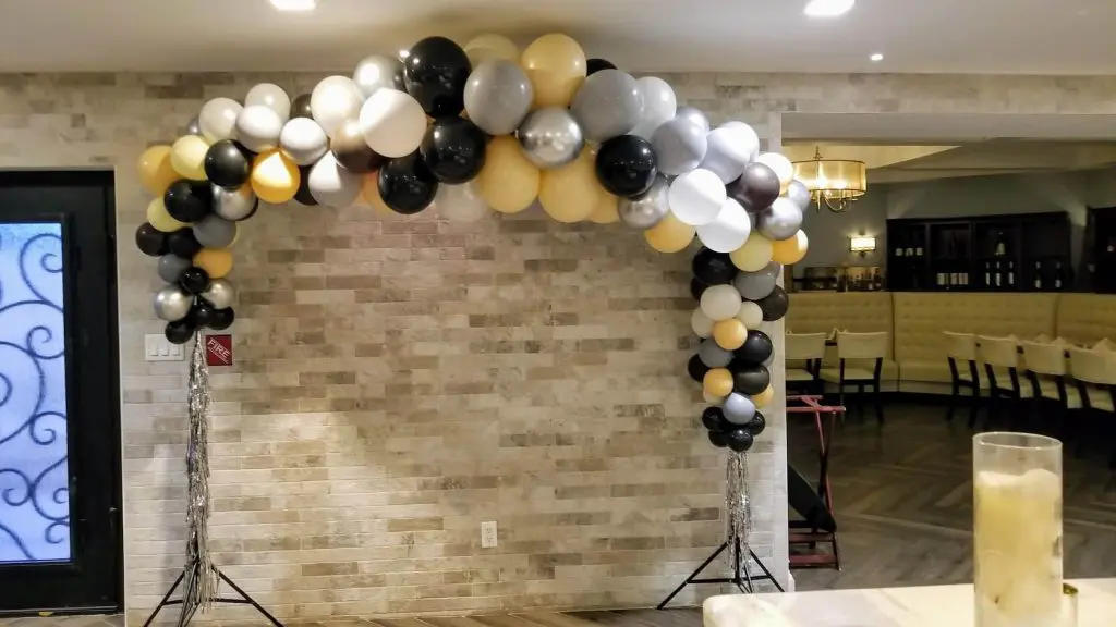 Balloons Lane in NJ showcases a stunning balloon decoration in shades of silver, yellow, black, and gray, arranged in an arch shape. The colors complement each other beautifully, creating an eye-catching display that's perfect for any celebration.
