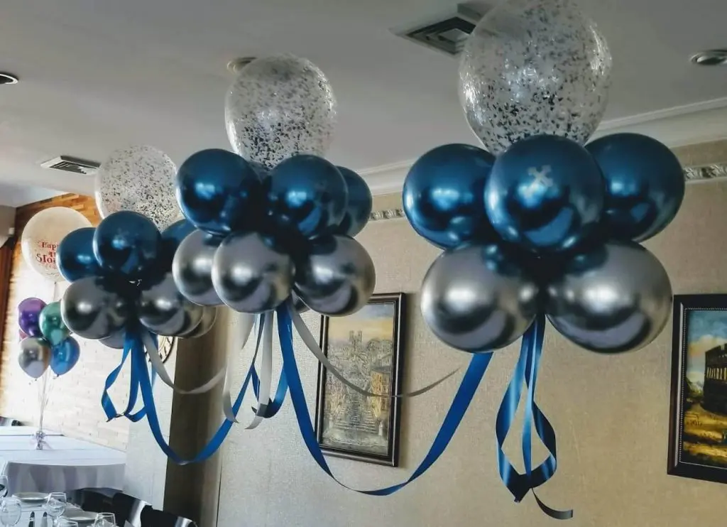 Silver and blue chrome balloons in a table arch with silver confetti for a birthday celebration
