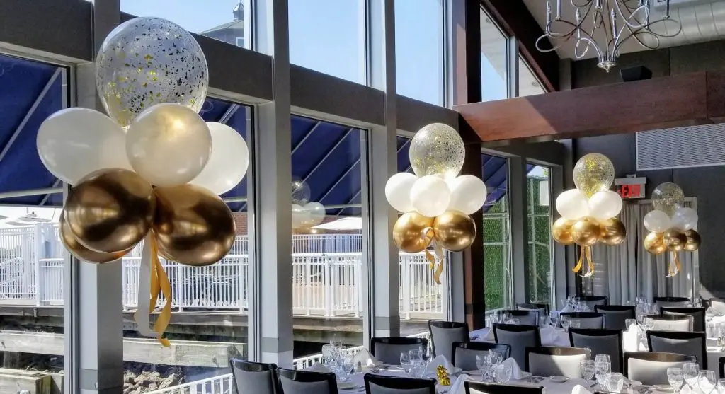 Gold and white balloon centerpieces with gold confetti balloons