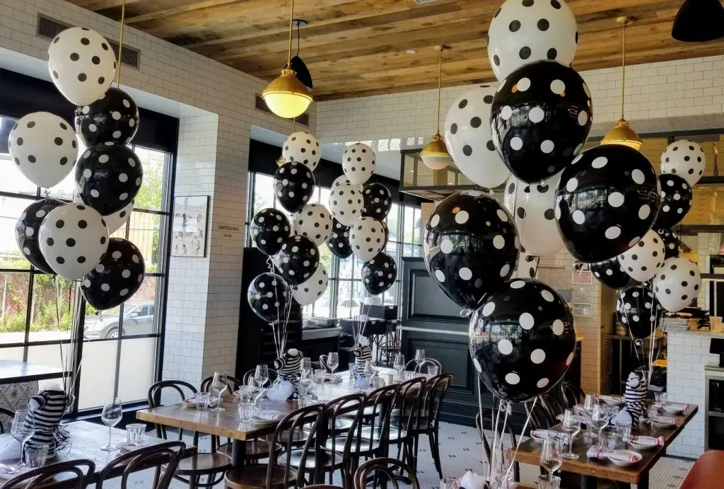 A playful and charming centerpiece for a baby shower, featuring black and white polka dot latex balloons arranged in a festive and decorative manner.