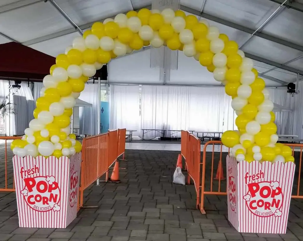 A balloon arch created by Balloons Lane in NYC, featuring yellow, rose gold, red, and white balloons. The colors are elegant and romantic, creating a celebratory atmosphere suitable for an anniversary.
