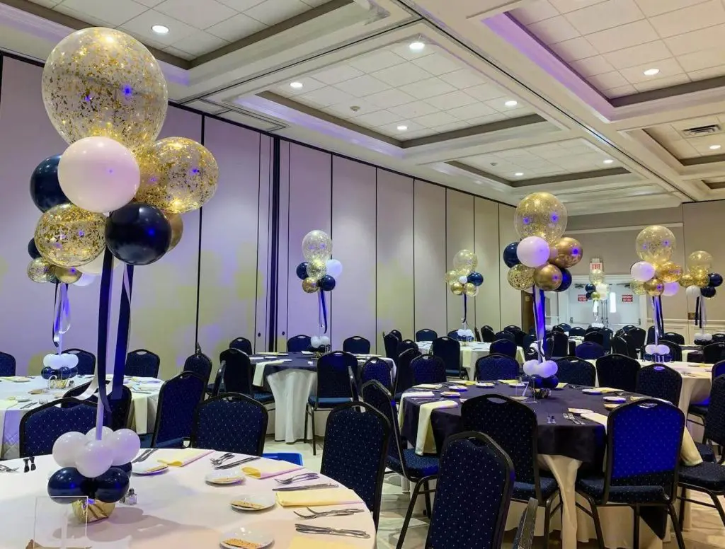 Beautiful bat mitzvah table centerpieces featuring midnight blue, gold, and white balloons arranged on Balloons Lane in New Jersey. The centerpiece includes a mix of large and small balloons tied to a weight and placed in the center of the table. The balloons create a fun and festive atmosphere for the event party