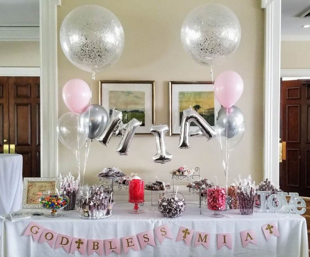 The decoration features pink and silver latex balloons arranged in a set on a dessert table, adding a celebratory touch to the thanksgiving-themed balloon centerpieces. The balloons are tied to weights at the base and create a joyful and lively atmosphere for the party.