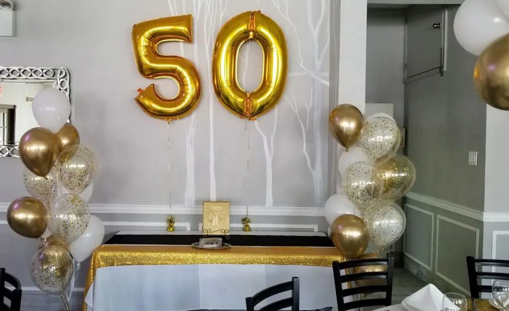 Gold and white latex balloons with confetti and large 50 Number balloon for a 50th celebration.