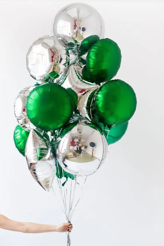 An elegant and festive centerpiece for an anniversary party, featuring round-shaped Mylar balloons in silver and green colors arranged in a decorative manner.