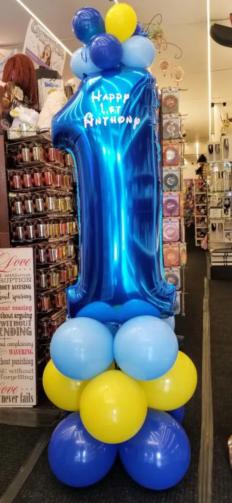 A yellow, Caribbean blue, and blue balloon centerpiece with number balloons 1, perfect for a first birthday celebration in Brooklyn.