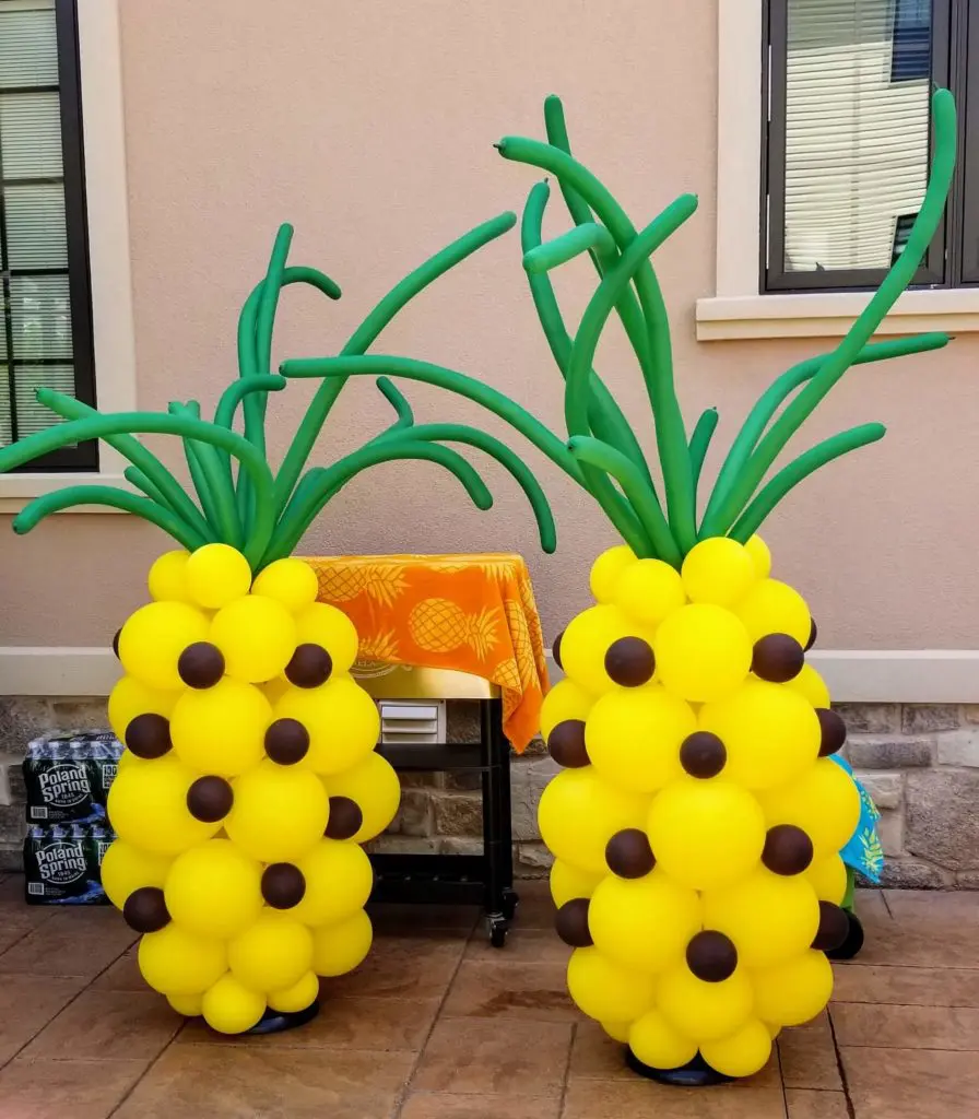 A colorful centerpiece of latex balloons in yellow, , green, and brown arranged in Pineapple shape by Balloons Lane in Brooklyn.