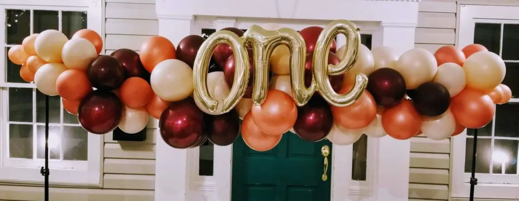 A stunning balloon arch featuring Sparkling Burgundy Chrome Copper and Chrome Gold balloons, along with Letter balloons spelling out "one" in Chrome Gold, perfect for kids birthday balloons decoration.