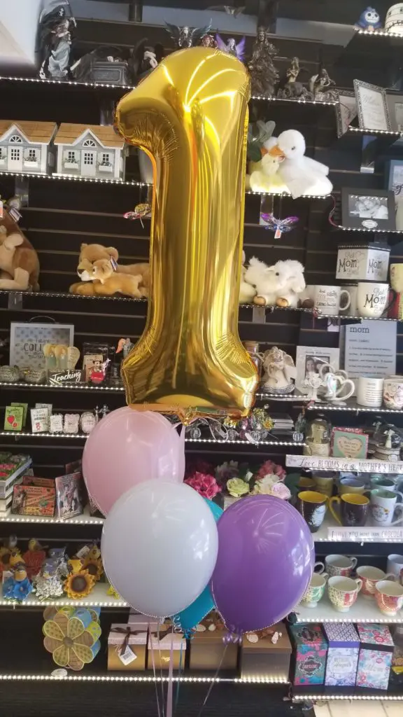 A garland centerpiece of balloons featuring white, pink, azure, purple, and gold colors, along with number balloons in gold, arranged in NJ.