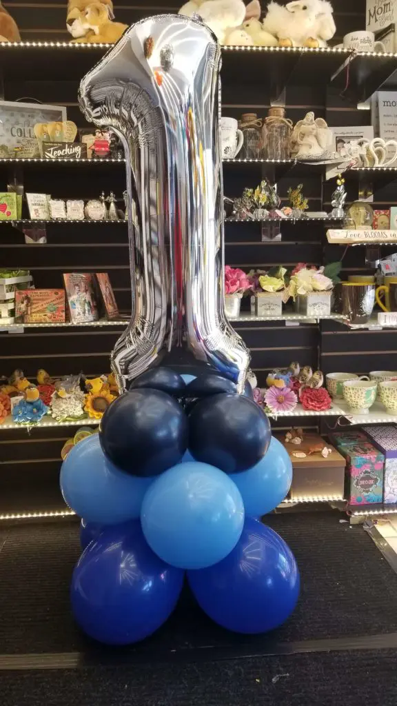 A tall column of balloons featuring purple, azure, black, and silver colors, along with number balloons in silver, arranged in NYC.