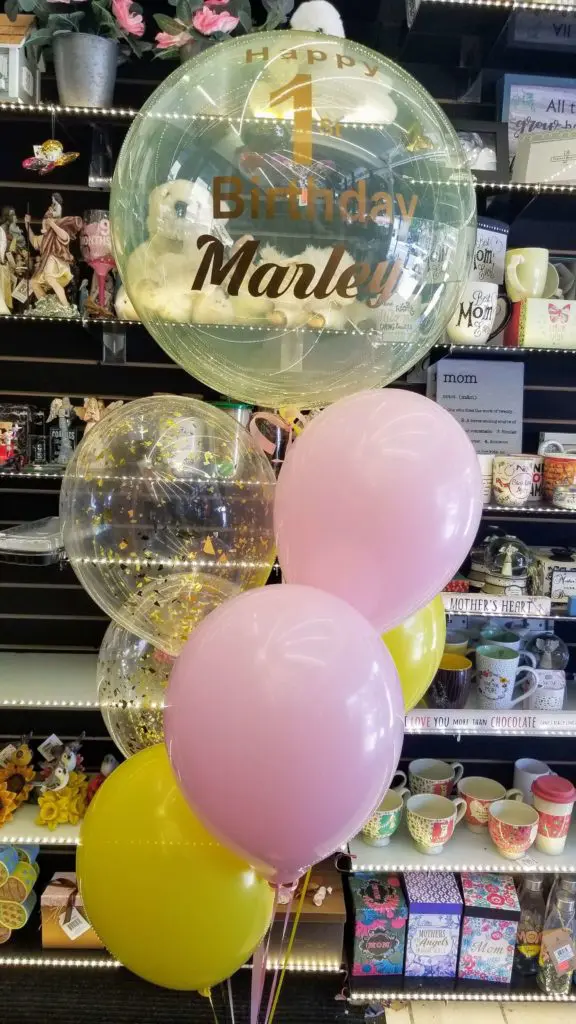 Yellow, pink and gold balloons with big round balloons in white centerpiece and customized clear balloon with written message in New Jersey.