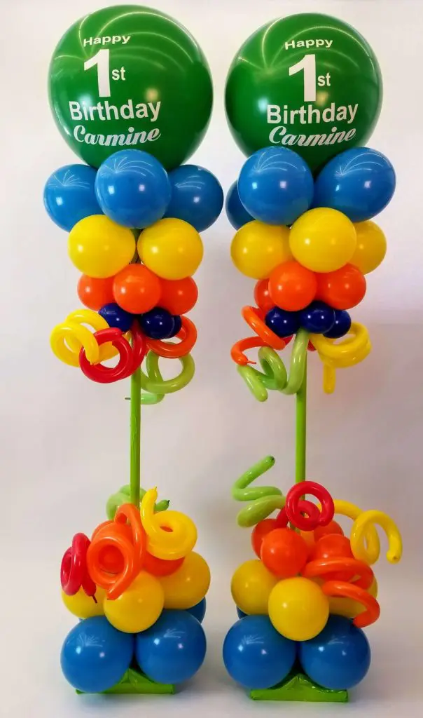 A vibrant balloon centerpiece in Azure, Yellow, Orange, Winter Green, and Emerald Green colors, featuring 1st Birthday balloons,