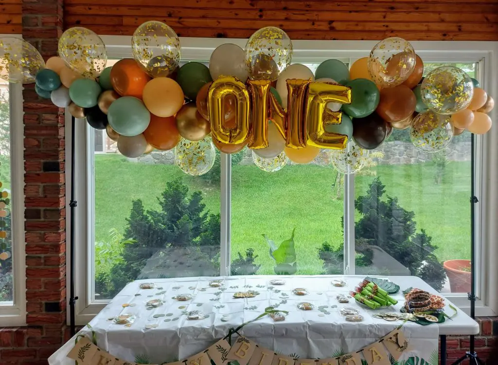 A beautiful balloon arrangement in chocolate brown, orange, winter green, chrome gold, lemon chiffon, and gold colors, featuring gold number 1 balloons as the centerpiece, created by Balloons Lane in New York. Suitable for baby first birthday celebration, first anniversary or business success celebration.