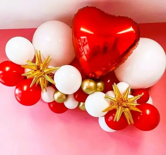 A collection of Valentine's Day balloons in red, chrome white, and chrome gold with burst star and heart-shaped designs.
