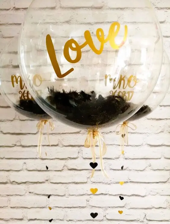Alt text: Balloons Lane's gold and chrome gold balloons with a big round clear black with heart strings and transparent balloon for Valentine's Day decorations.