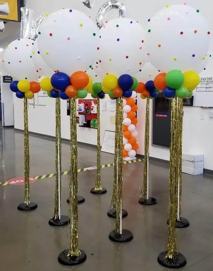 Colorful balloon display featuring white big balloons with orange, blue, and yellow small balloons, accented with gold tassels stands, perfect for adding a fun touch to any event.