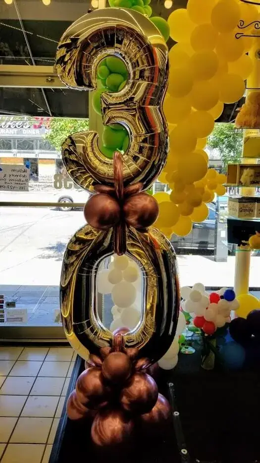 A stunning balloon column featuring a 3 and 0 balloon, with brown round chrome balloons, perfect for a milestone celebration.