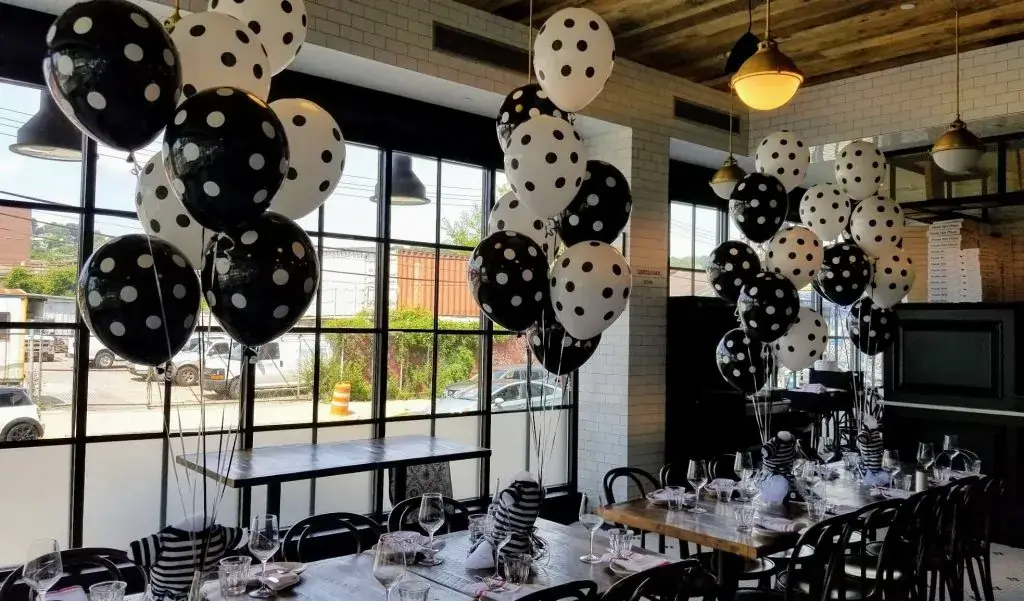 Chic and elegant black latex balloons with white polka dots, paired with solid black balloons and a matching balloon weight, perfect for creating a stylish and sophisticated centerpiece for any party or event.