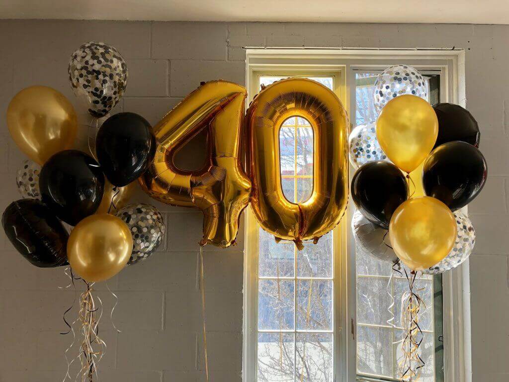 Stylish balloon arch with black confetti and gold chrome balloons and a large 40 number balloon.