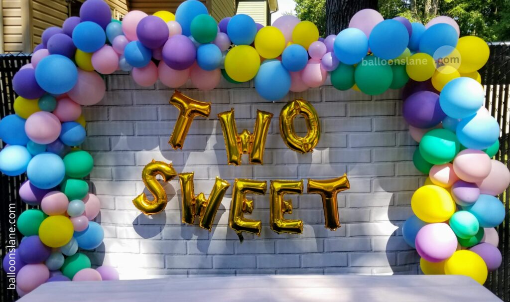 Balloons Lane in NYC creates a beautiful Easter butterfly-themed sweet 16 party decoration using pink, yellow, gray, green, gold, sky blue, and purple bouquet balloons