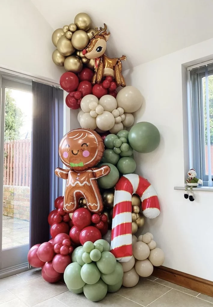 Balloon backdrop in Ivory Silk, Red, Pearl Ivory, Chrome® Gold, and Pearl Mint Green, adorned with candy balloons, gingerbread balloons, and a Christmas deer foil balloon.