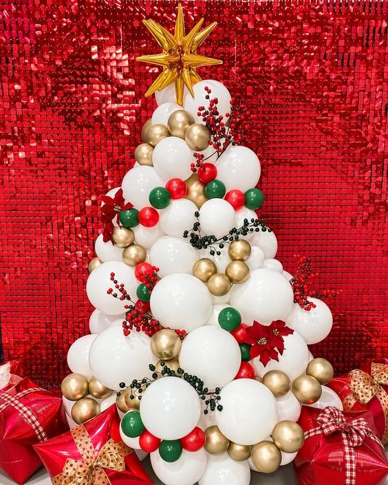 Gold star Mylar balloon surrounded by a centerpiece of white, green, red, and gold balloons, accompanied by charming gift balloons for an extra special Christmas party.