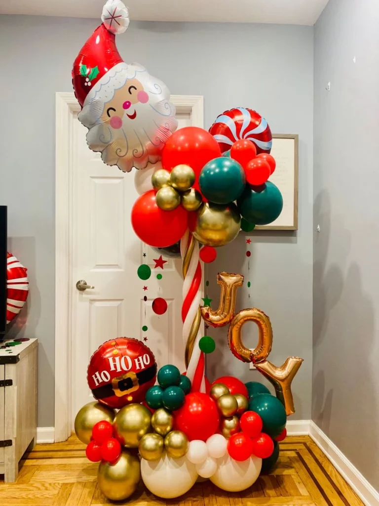 Santa balloon column featuring a "HoHo" red foil balloon, along with green, red, white, and gold latex balloons in various sizes, JOY letter balloons, and candy balloons to double the joy of the Christmas party.