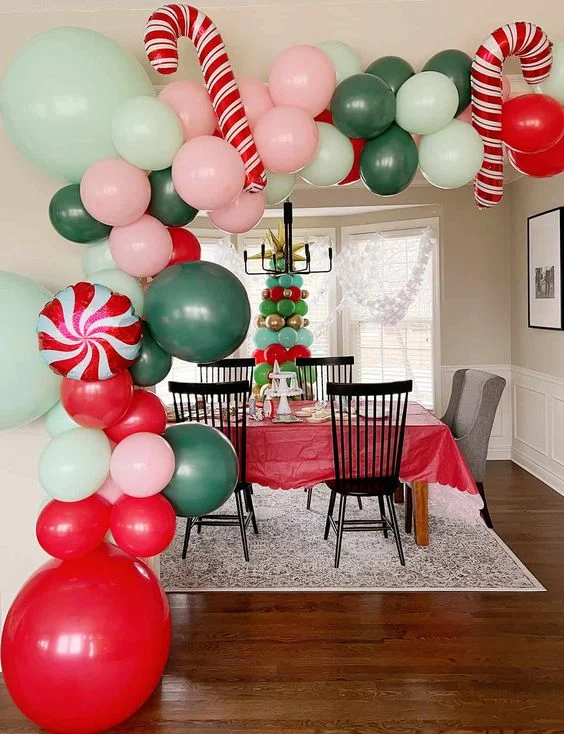 Festive Christmas balloon arrangement with candy balloons in red, green, gold, and dark green, complemented by a playful latex balloon garland.