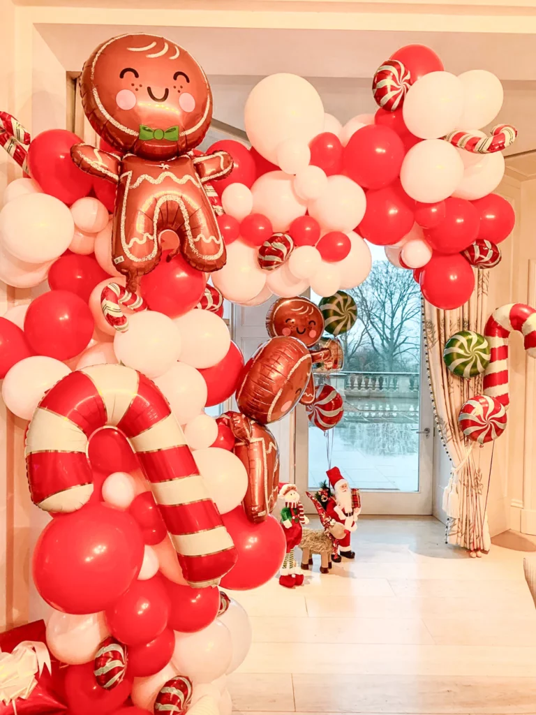 Balloons Lane's creative and unique balloon Christmas party arch, featuring balloons in candy shades of red, white, and brown, along with gingerbread latex balloons.