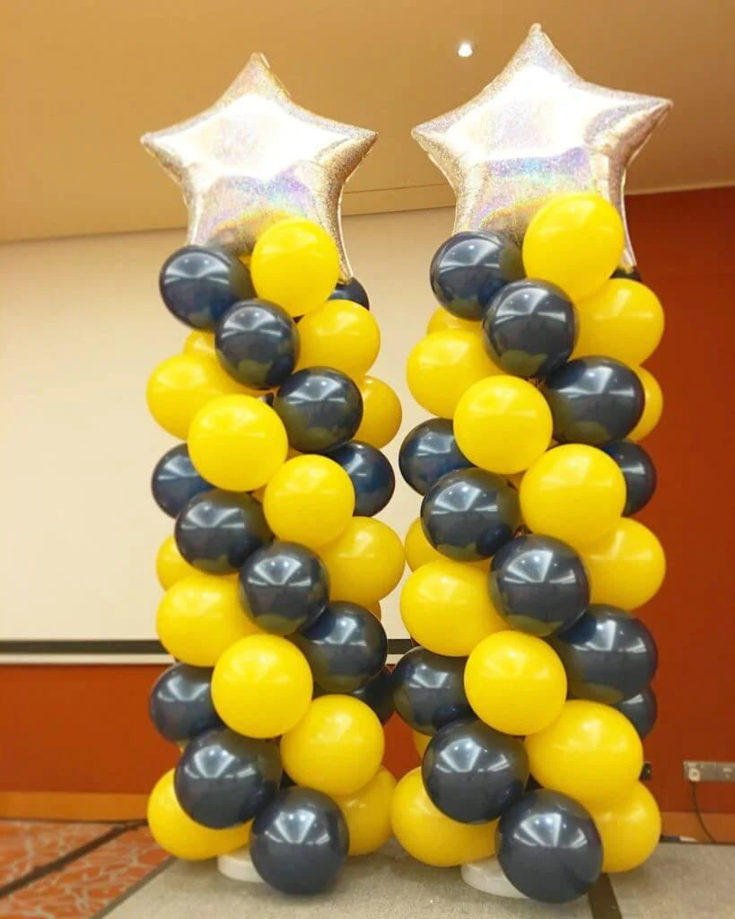 Chrome black and yellow balloons column with a big silver star balloon in the center, crafted by Balloons Lane in NYC for a stunning and dynamic event decor