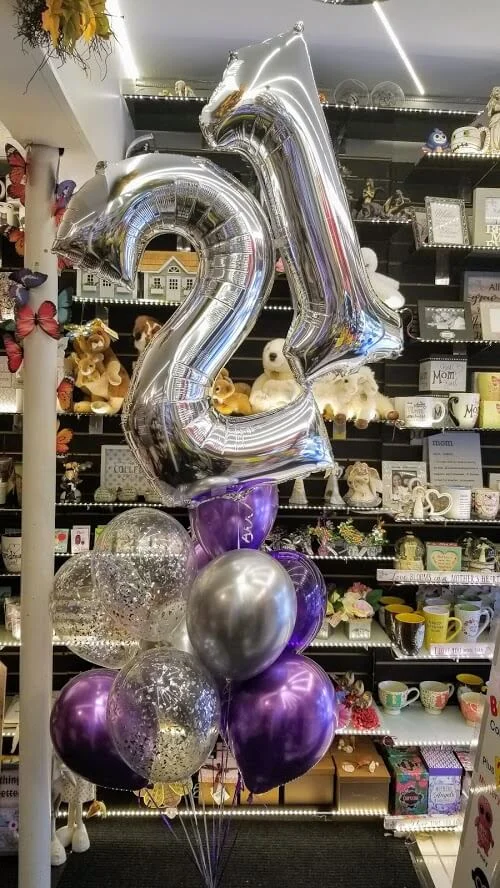 The silver "21" number balloon adorned with confetti in purple, accompanied by a bouquet of purple latex balloons. Ideal for Anniversary Parties, Birthday Parties, and all special events.
