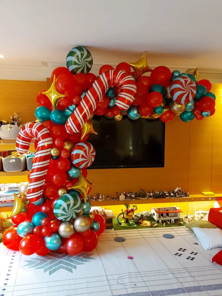 A creative and unique balloon Christmas party in arch featuring balloons in candy balloon of yellow red green gold purple dark green and white latex column balloons