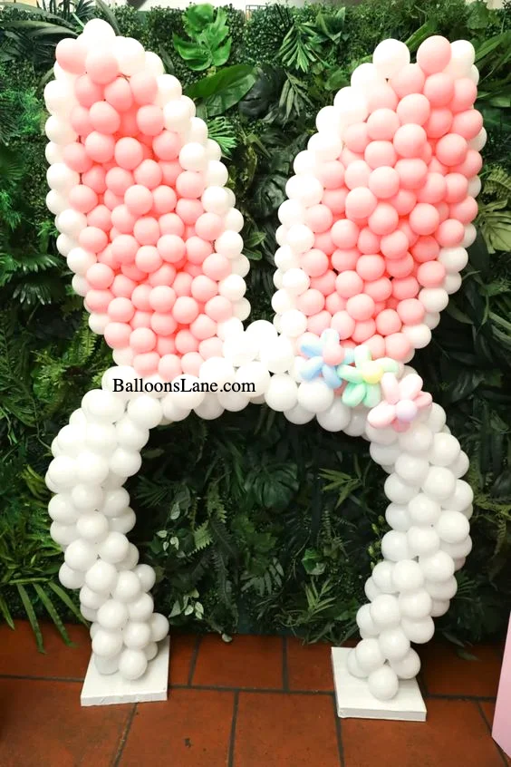 A captivating white bunny-themed balloon display surrounded by an arch of green and blue twisted balloon flowers, set against Brooklyn's backdrop.