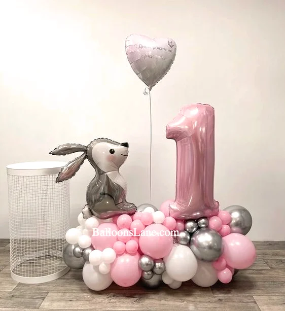 Beautiful textured pink balloon, clear heart-shaped balloon, pink shade balloon, and number "1" balloon on top of a silver heart foil balloon, rabbit balloon, and cluster of pink silver chrome balloons in NJ