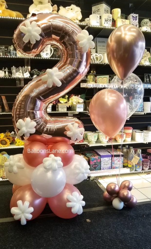 Number 2 balloon in rose gold, surrounded by rose gold and white balloons and a white flower balloon to celebrate a 2nd birthday in NYC.