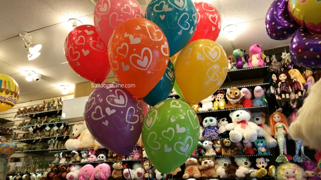Multi-color balloon bouquet featuring heart-printed balloons in red, orange, pink, yellow, green, and purple.