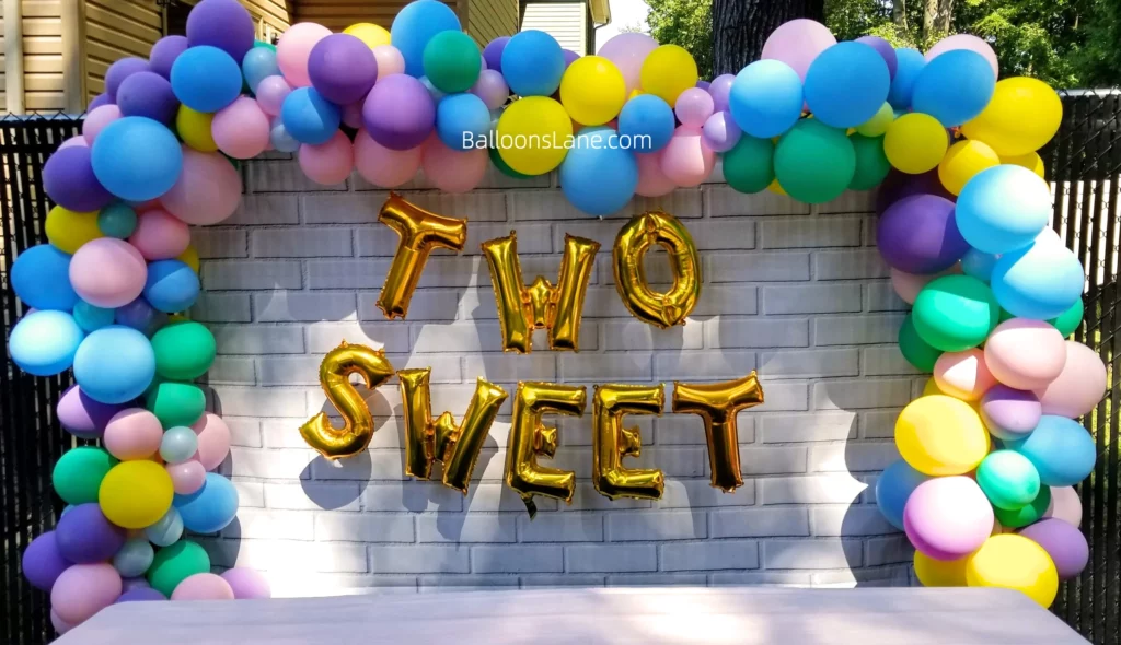 Colorful Balloon Garland with Purple, Pink, Yellow, and Green Balloons, Accompanied by "Two Sweet" Letter Balloons to Celebrate 2nd Birthday
