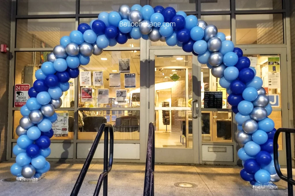 Arch made of royal blue, light blue, and white latex balloons with silver balloons at the school.