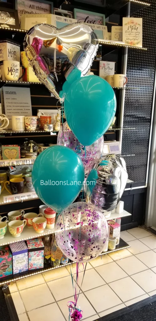 Balloon bouquet featuring a silver heart balloon, purple confetti balloon, and blue latex balloon.