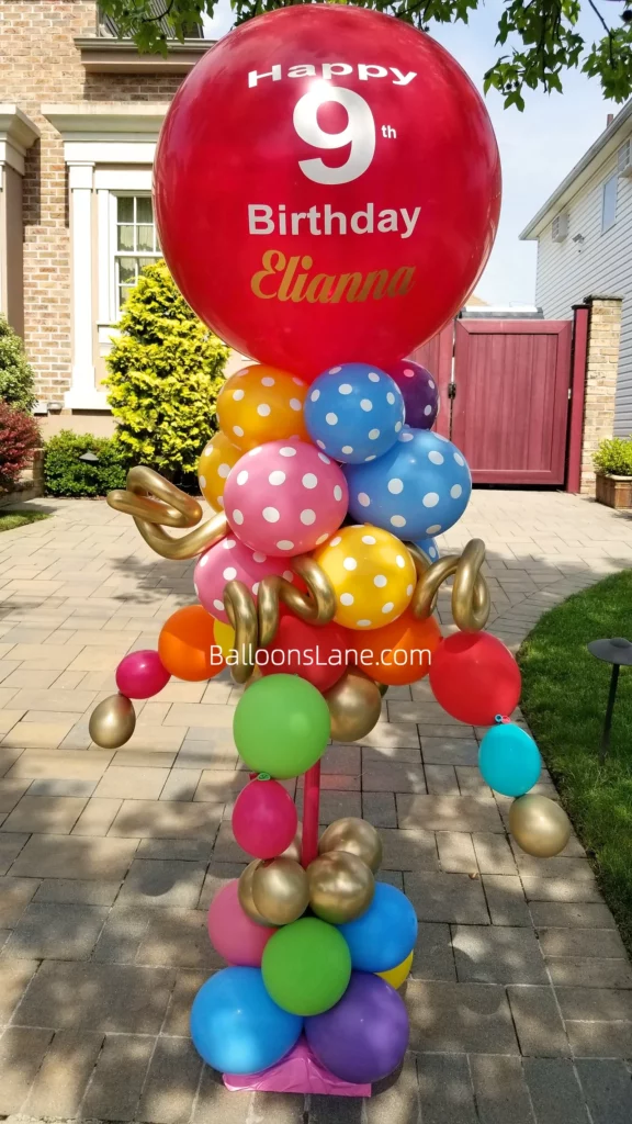 Happy 7th birthday balloon bouquet with yellow, orange, blue, and green balloons, and a large red personalized balloon in NYC along with gold twisted balloon