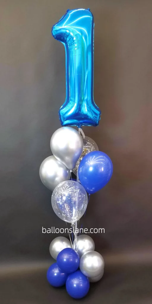 Celebrate a 1st birthday in New York City with a charming display featuring shades of blue, blue balloon, silver balloon, and blue number balloons.