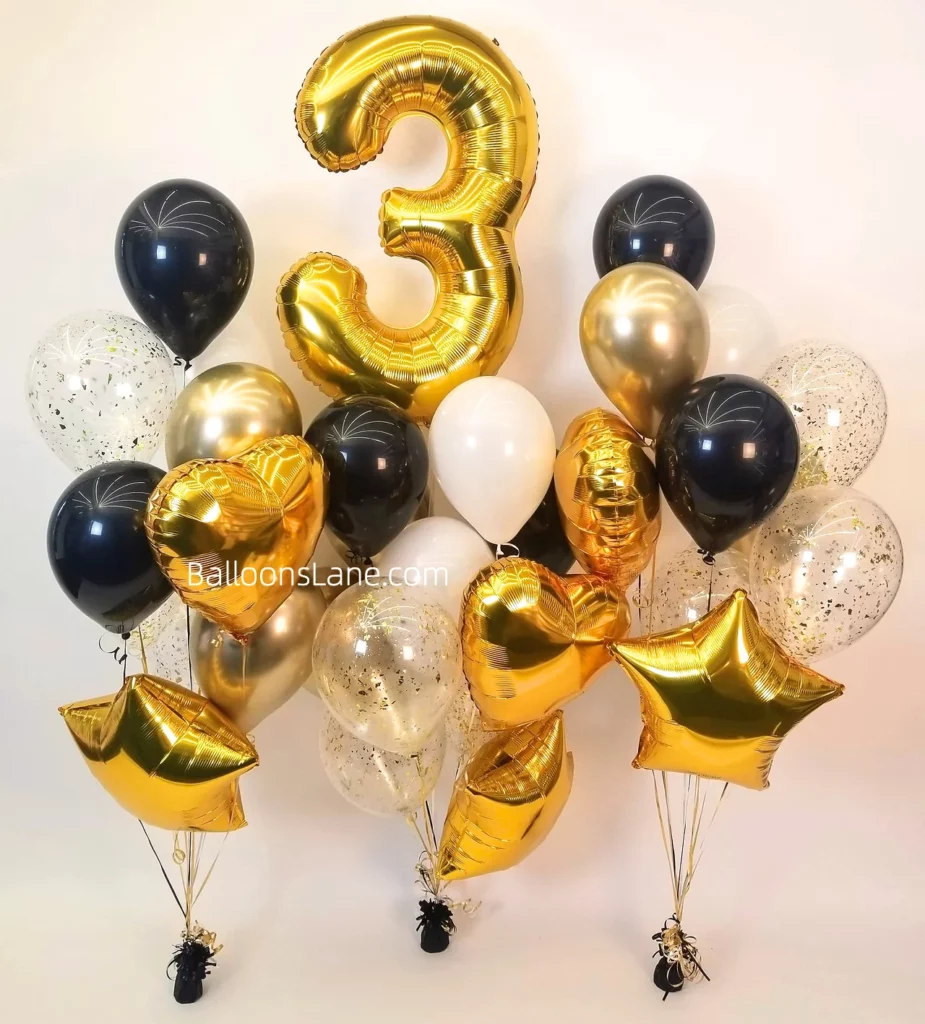 Large number 3 balloon centerpiece surrounded by chrome gold and black latex balloons, a gold star balloon, and a confetti balloon for a birthday or anniversary celebration arranged in a bouquet to celebrate 3rd birthday.