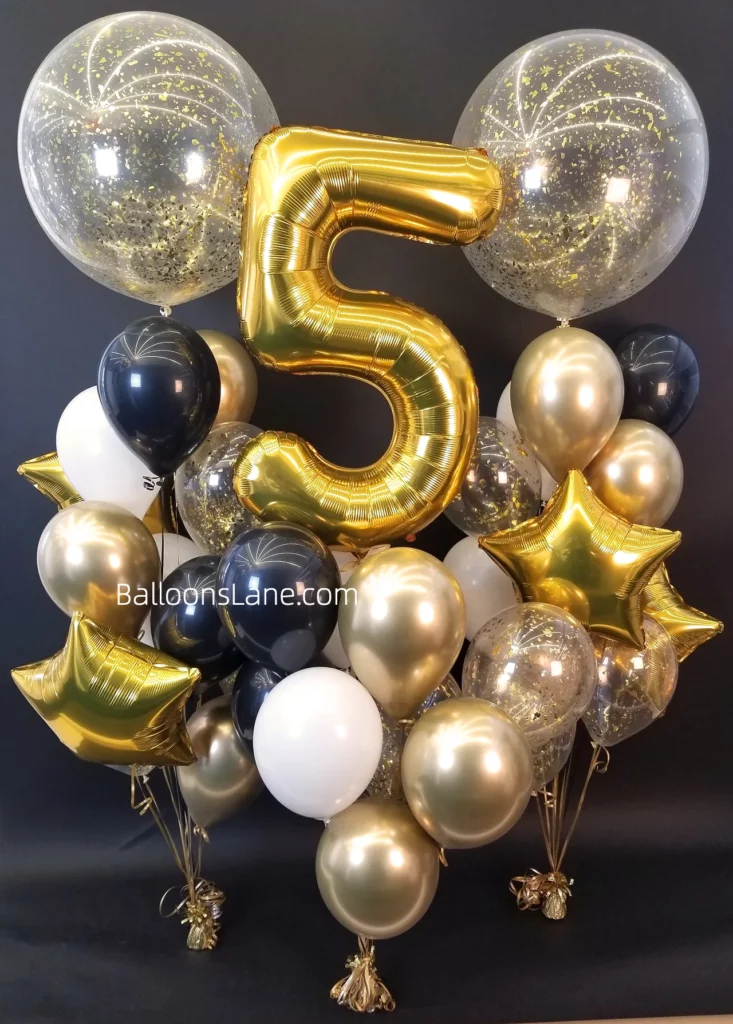 : A large number 5 balloon centerpiece surrounded by chrome gold and black latex balloons, a gold star balloon, and a large confetti balloon for a birthday or anniversary celebration.