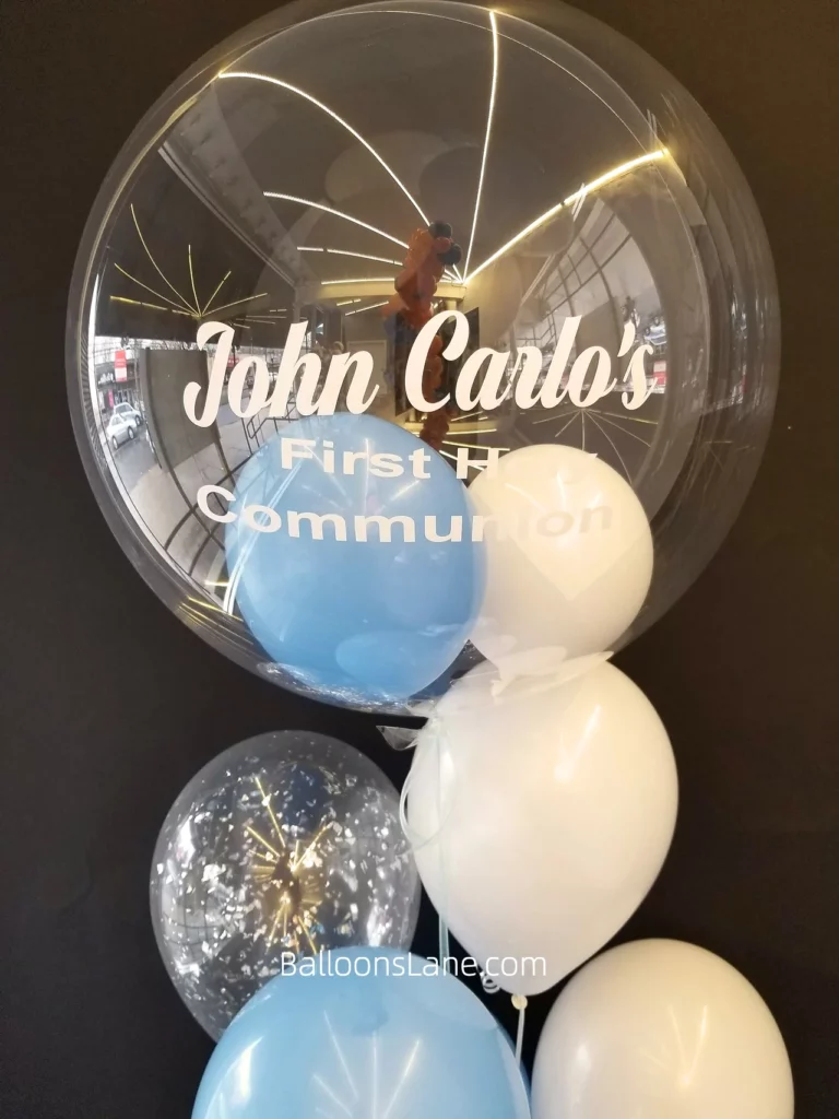 custom balloon arrangements feature a stunning combination of white, blue, and confetti balloons, along with a special Communion or christening big cross Mylar balloon bouquet.
