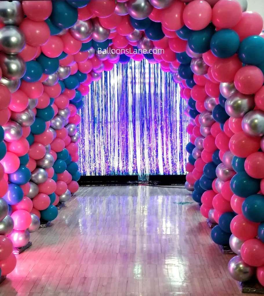 Arch made of pink, sea green, and gold balloons.
