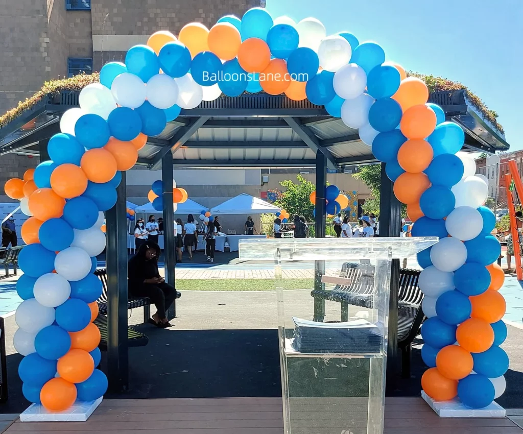 Arch made of orange, light blue, and sky blue balloons at the school event.